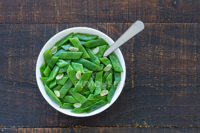 From above of healthy salad with green beans and garlic slices in bowl served on wooden table — Stock Photo