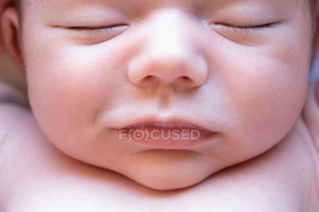Top view of cute small adorable naked newborn baby sleeping lying on soft bed at home — Stock Photo